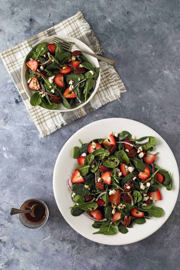 strawberry spinach goat cheese salad in a bowl with dressing